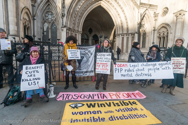 Women outside the Royal Courts of Justice holding placards including: "Today: Legal challenge against PIP rules about people with mental distress".  Benefit cuts are killing us! Traumatised women deserve DWP support -- Women Against Rape.  Coping with mental distress is hard work -- We demand full PIP for mobility.