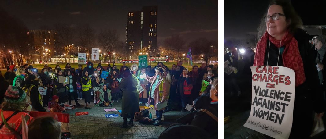 Night time in Walthamstow Town Square.  A crowd of women and girls, some holding placards and flags, is gathered around a woman with a headscarf who is speaking.  Someone next to her holds a lamp which shines brightly.  Behind is a green space and a tower block.  Ariane from WinVisible wears a placard: Care charges = Violence Against Women.