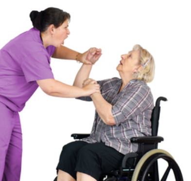 Posed photo of a woman in homecare uniform standing over an older woman wheelchair user, shouting at her and getting physical, pushing her arms which are raised.