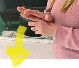 A deaf woman is making the BSL sign for discrimination: a person represented by upright finger is pushed down by the other hand.