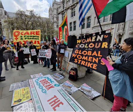 A crowd has gathered in a corner of Parliament Square in front of the Free Mumia banner and various others banners. Placards against wrongful imprisonment are laid on the pavement.