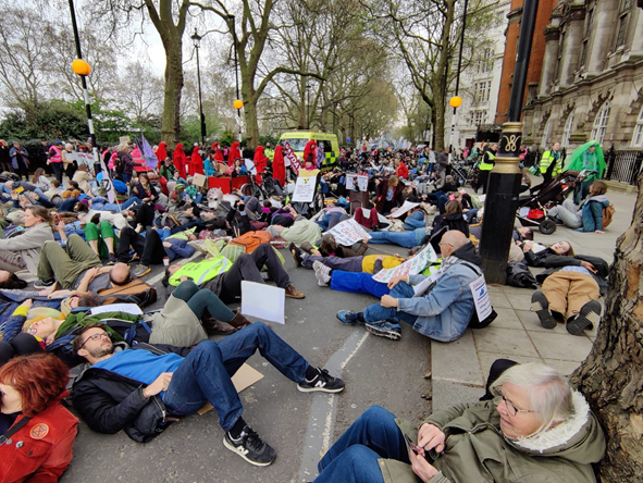 People lying in the road along Millbank. There are thousands who stretch far into the distance.