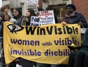 WinVisible women holding our banner and placards at a protest against care charges.