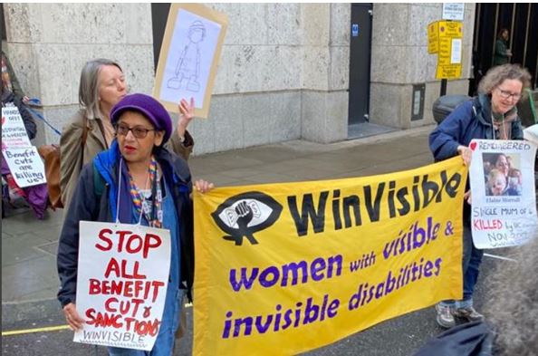 Women carrying the WinVisible banner at DWP protest. A placard says: Scrap all benefit cuts & sanctions.