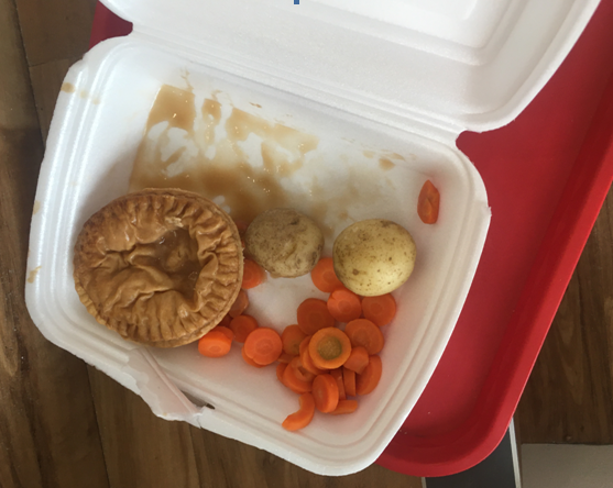 A takeaway box less than half full. A small pie, slices of carrots and two small boiled potatoes with a smear of gravy inside.