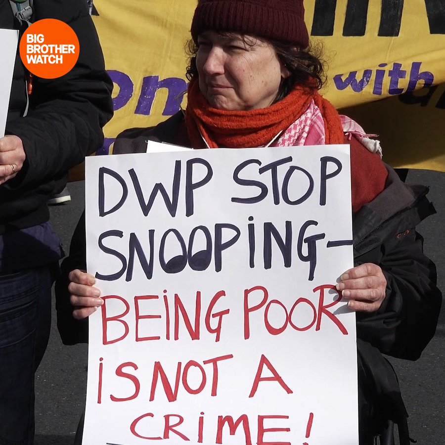 A woman wheelchair user holds placard: DWP stop snooping -- being poor is not a crime!