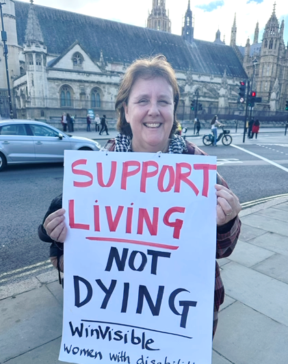 With the Houses of Parliament in the background, Tracey Norton holds a placard, Support living not dying -- WinVisible
